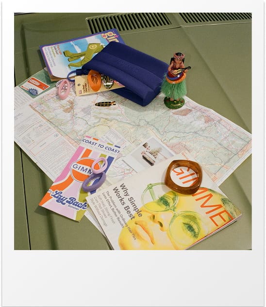 Collection of items including a map, books, and a figurine on a green surface.